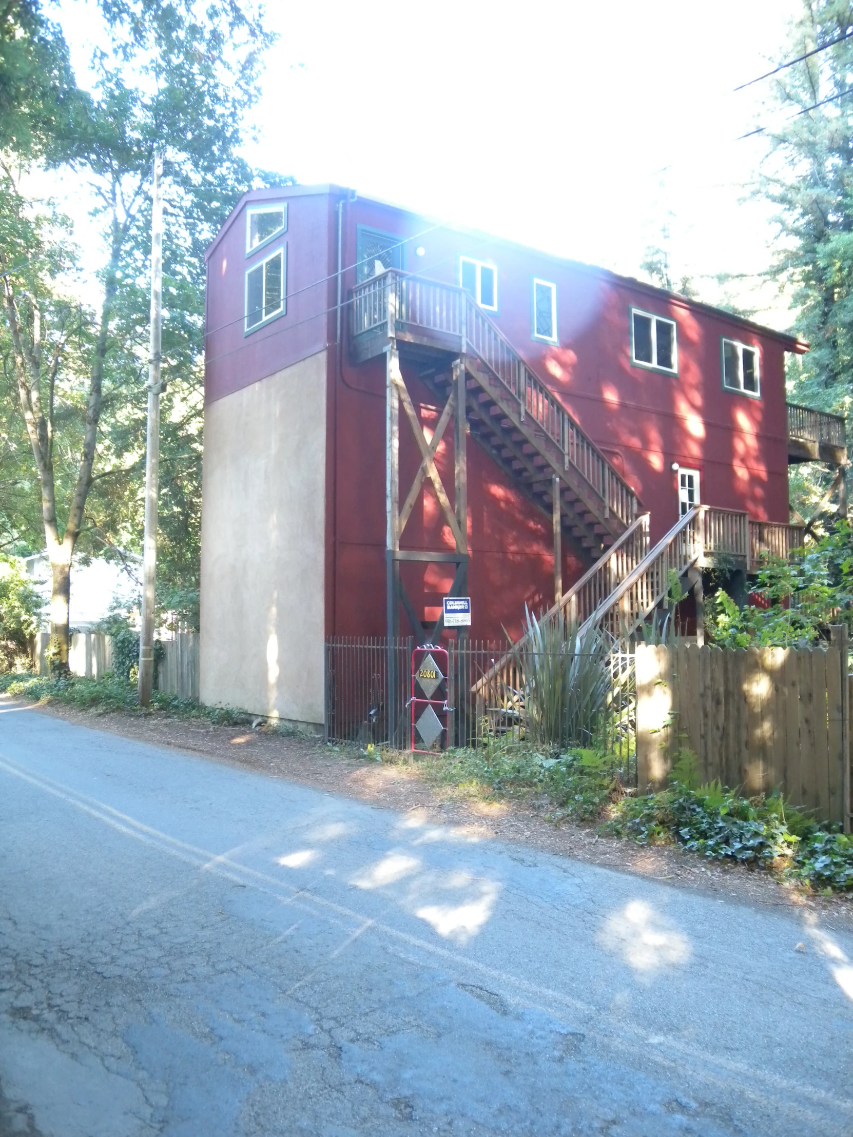 a house with some stairs on the side and a car parked in front