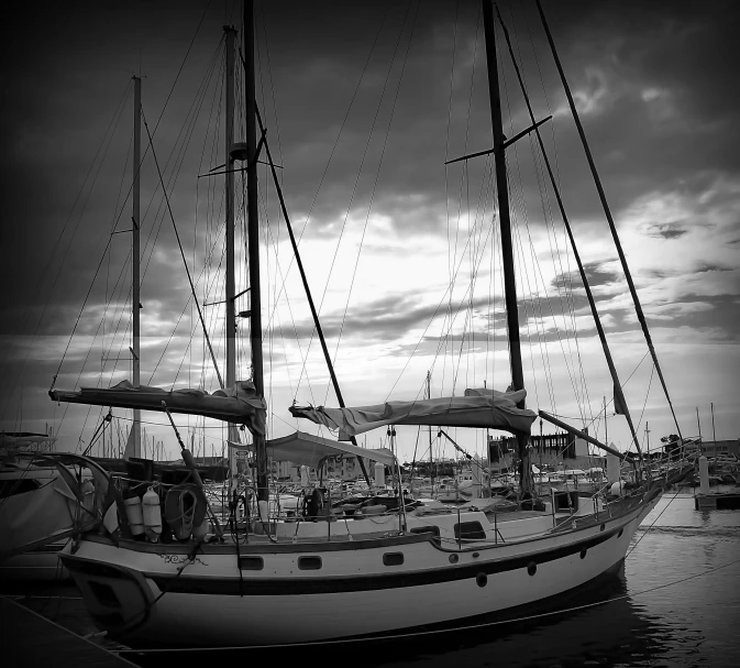 a sailboat docked at a dock under a cloudy sky