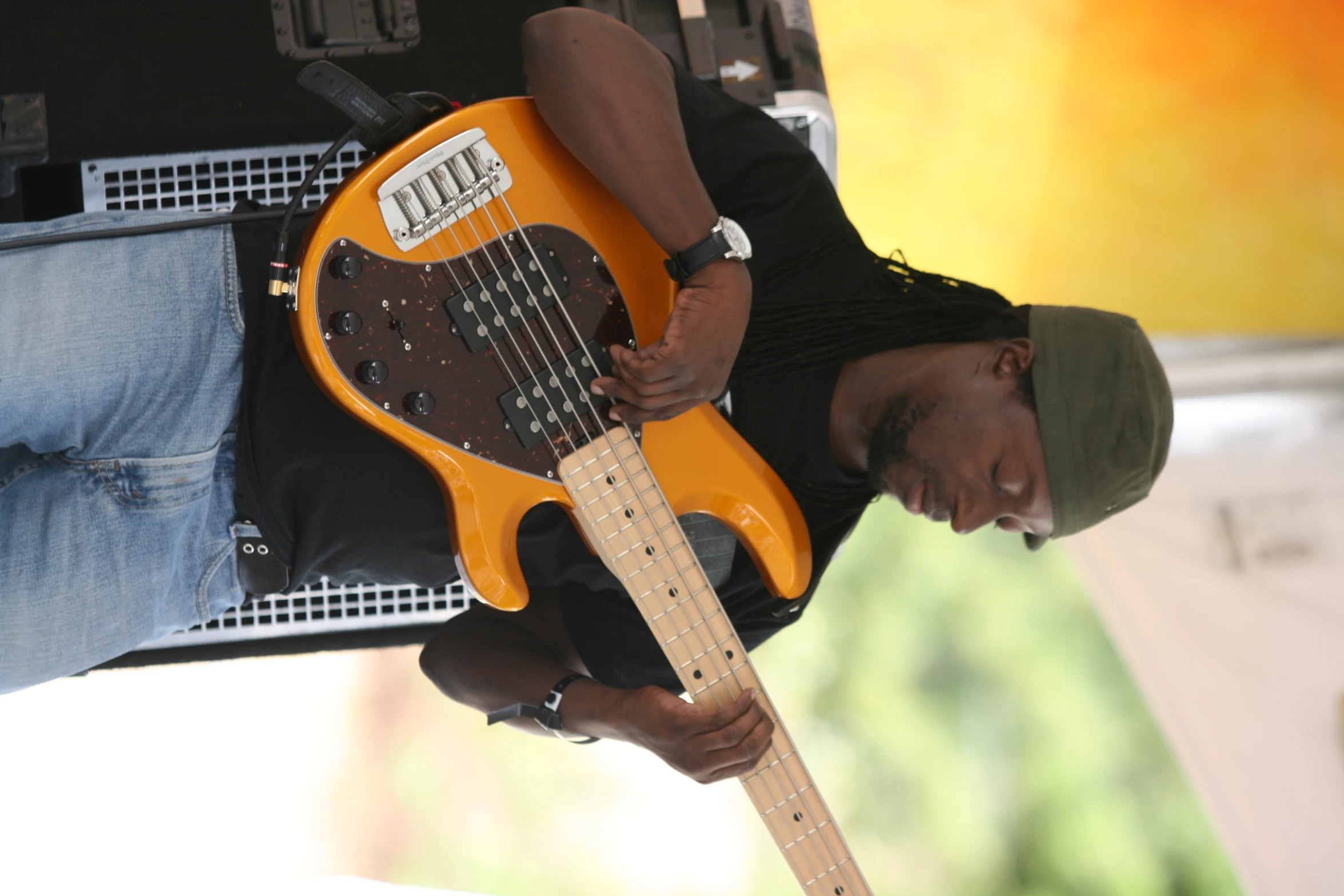 man holding an orange guitar while standing on stage