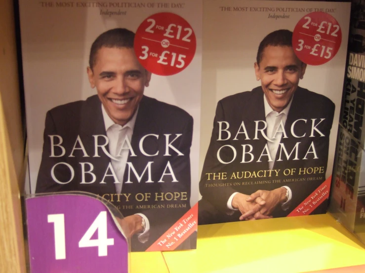three barack obama signs next to a pile of books