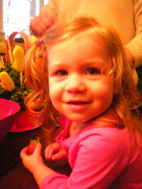 a small girl sitting next to some green fruit