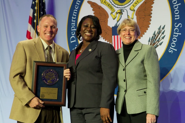 three people posing for a picture and one woman holding an award