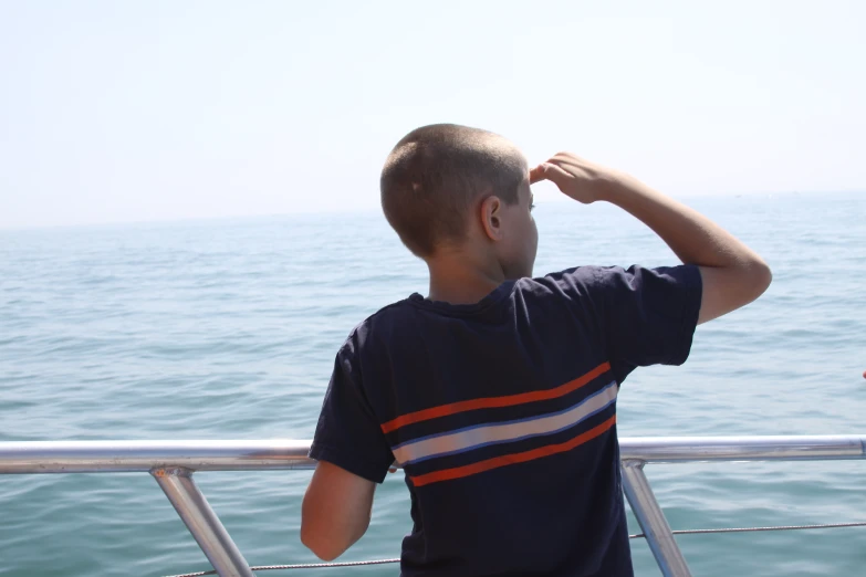 a boy with his hands up on the edge of a boat