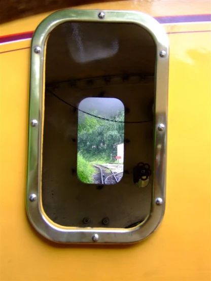 a mirror on a yellow wall in the shape of a small window