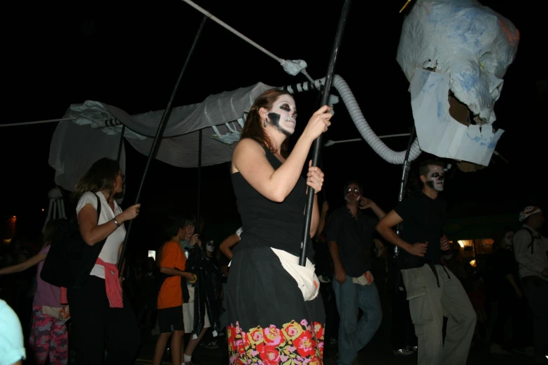 a girl in a dress holding a long metal wire with her face painted