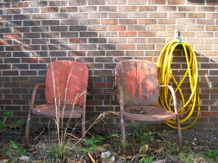 a yellow hose and two chairs sitting by a wall