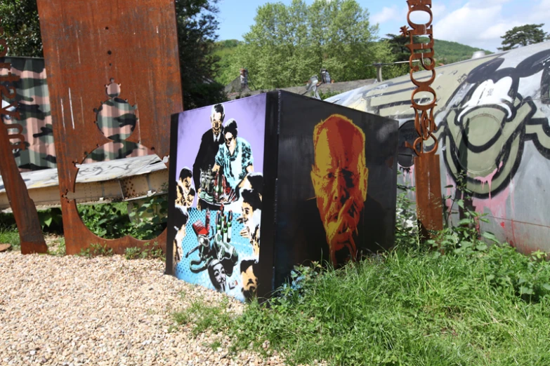several paintings on some steel poles in the grass