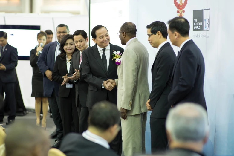 two men and one woman hold hands as others stand close to the wall