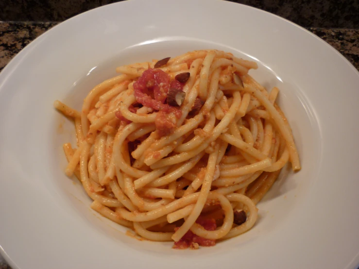 there is pasta with sauce and some meat on a white plate