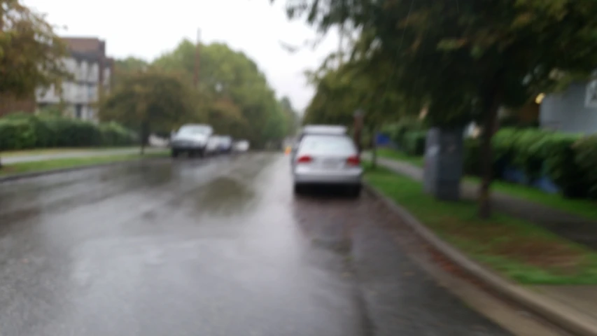 two cars parked at the curb and three people walking down the street