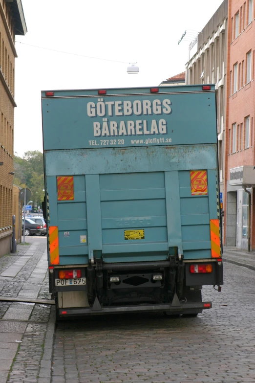 a blue delivery truck traveling down a cobblestone road