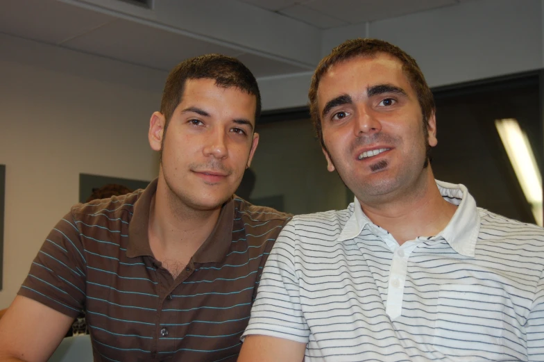 two men sitting together smiling and looking at soing