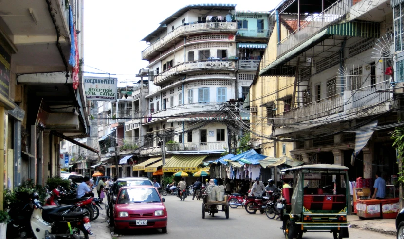 a small red car driving down the street near a large building