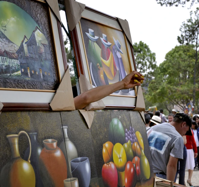 the man is painting several colorful pictures outside