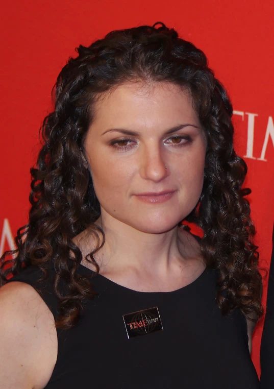 woman wearing a black dress standing in front of a red wall