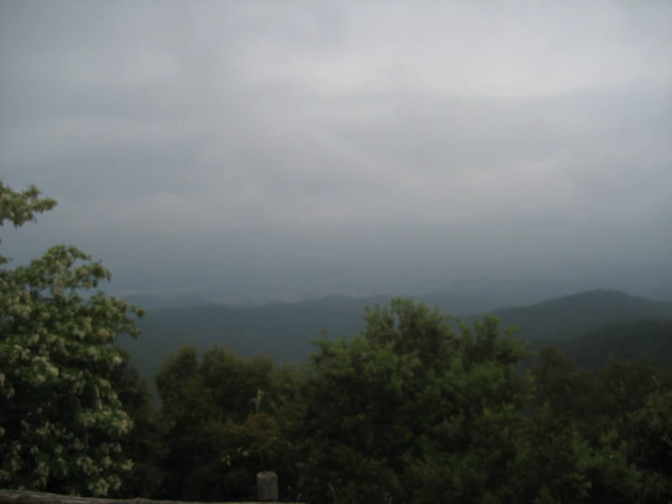 a green hillside covered with trees and mountain ranges