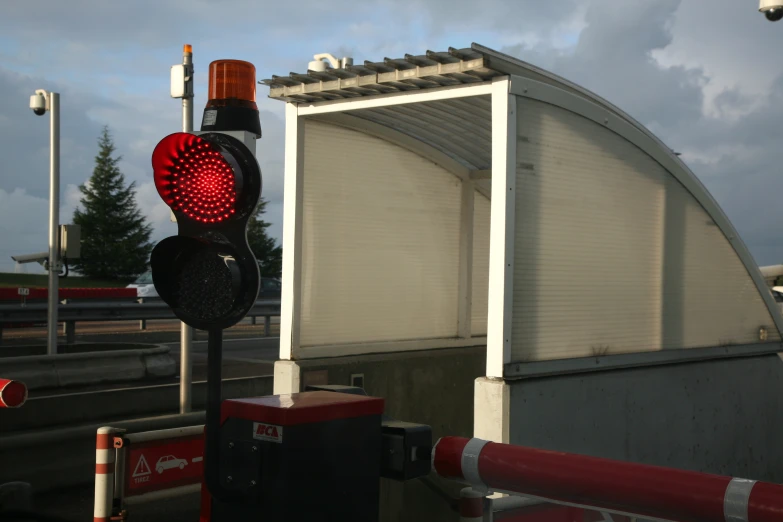 a red light on a metal pole in front of a building