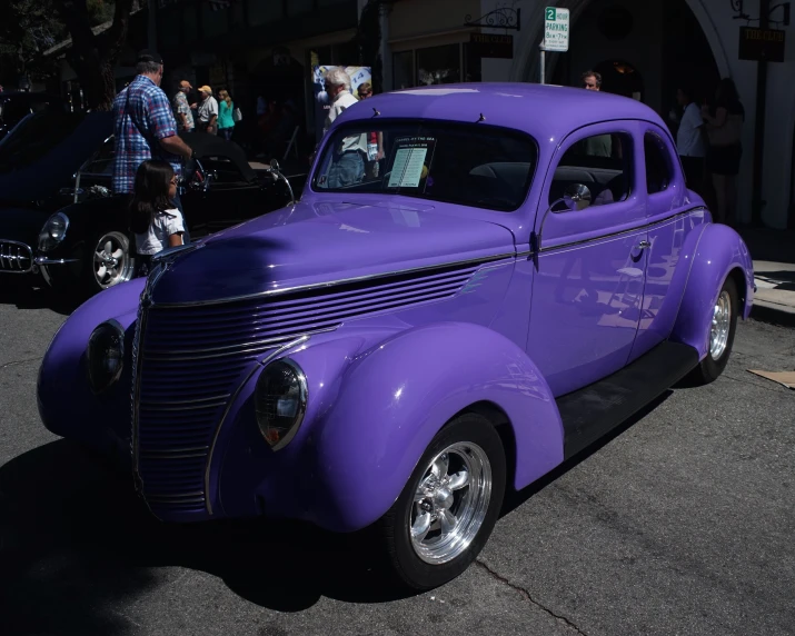 an old purple car is parked near other cars