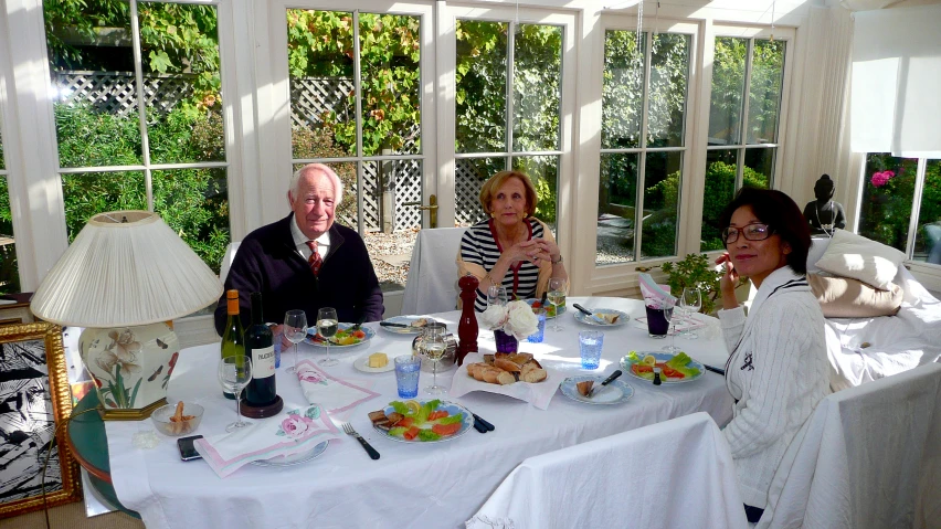 three people seated at a table with food and wine