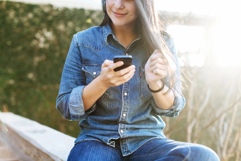 a girl sitting on a wooden step using her cell phone