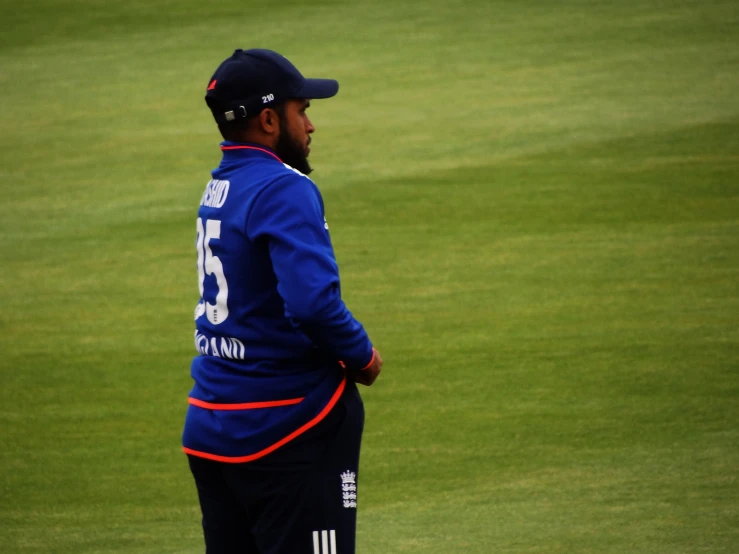 a young man in a cricket uniform stands on the field