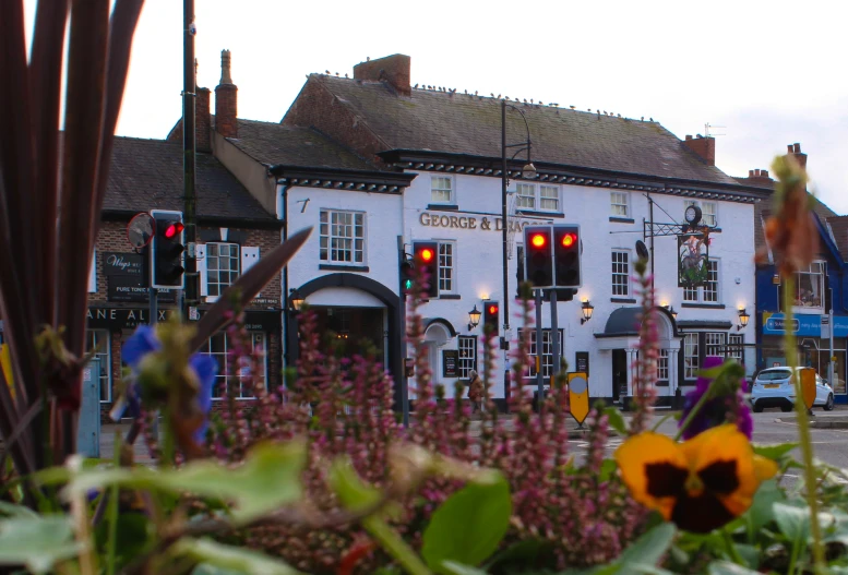 an intersection in a small town with cars and flowers