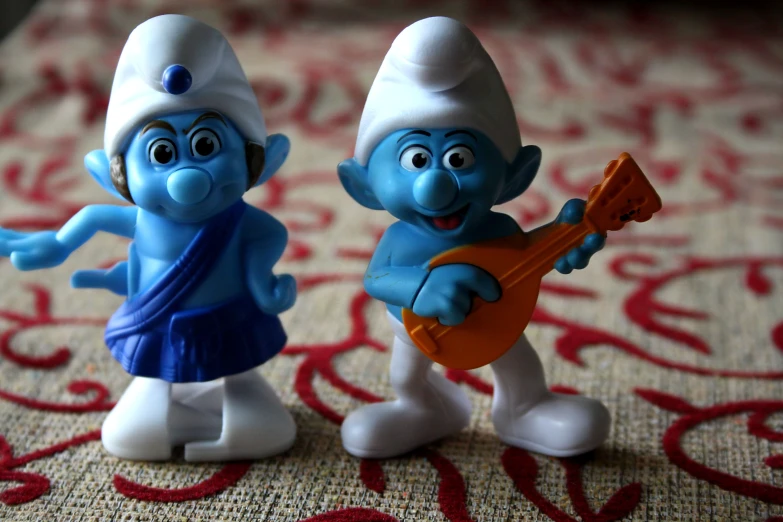 two small blue and white figures playing on a red carpet