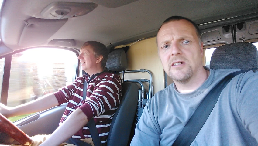 two men are riding in a bus on the street