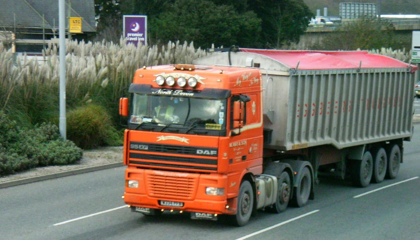 a bright red and silver truck on street next to bushes