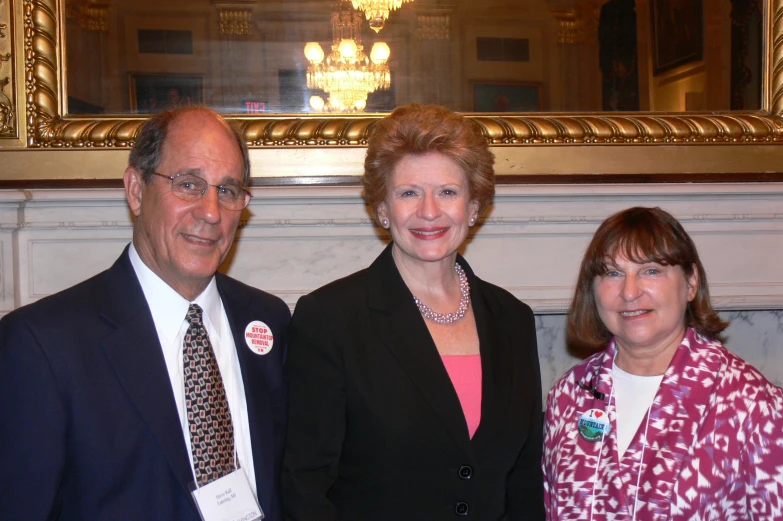 three people standing in a room, one is smiling