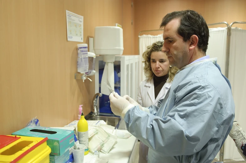 a man and a woman preparing dental equipment for 