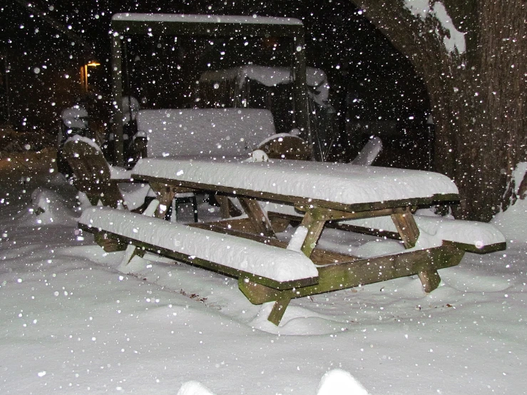 a picnic table covered in snow near a house