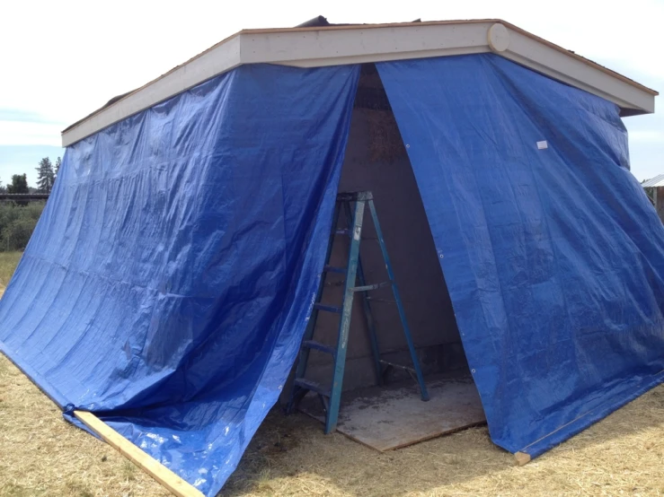 a blue tarp in the ground and a yellow frame