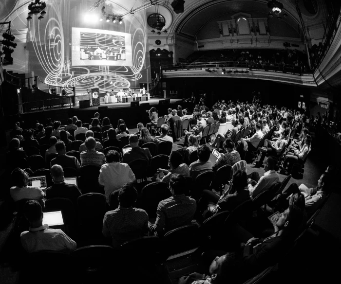 an auditorium with people seated and the lights on