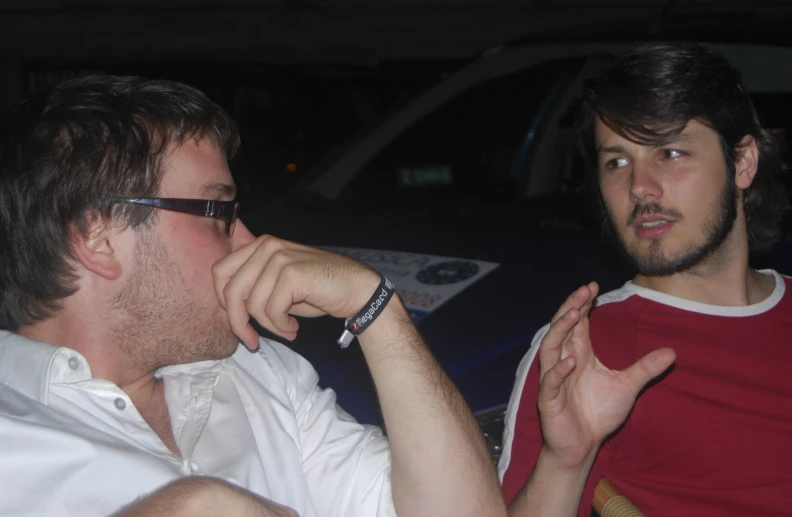 two men are sitting together, both wearing glasses