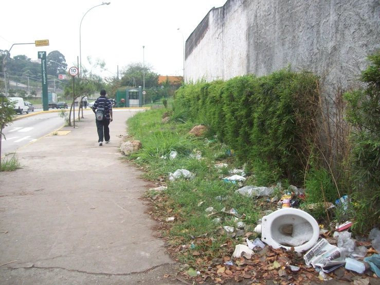 a man walks along the sidewalk with trash
