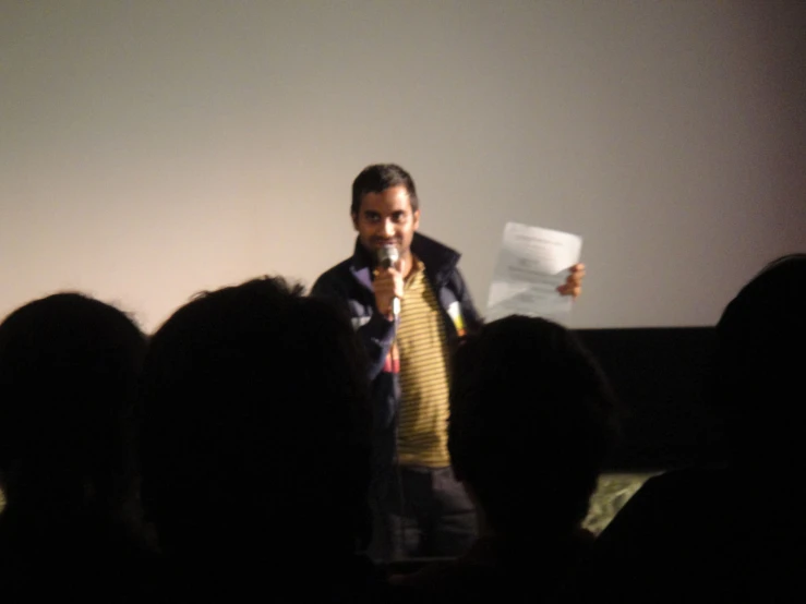 a man standing in front of a crowd while holding a paper