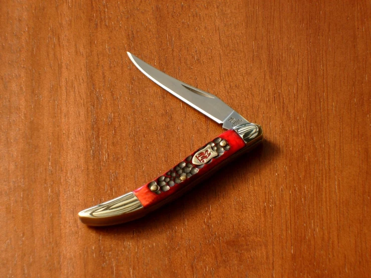 an orange and gold colored pocket knife with white trim