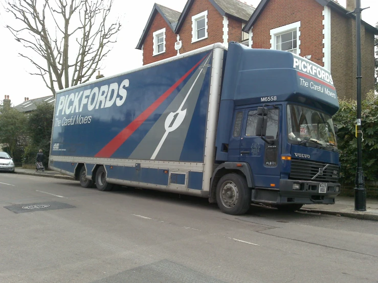 an empty blue delivery truck parked by the side of a road