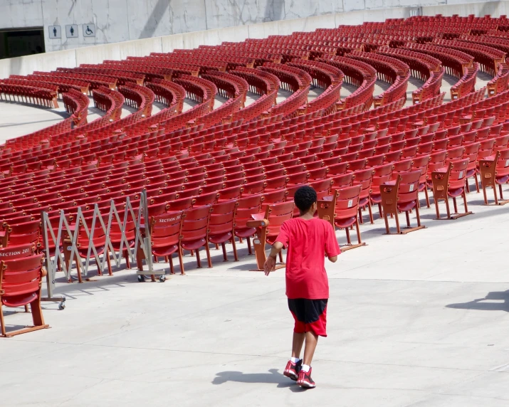 a boy playing with a red tennis racquet in front of a full stadium