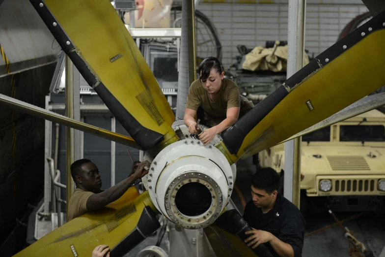 a woman and two men examine an airplane propeller