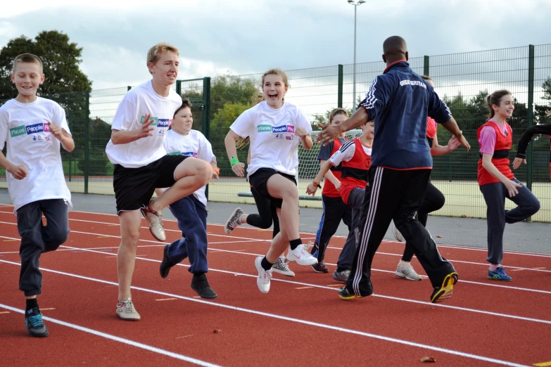 several young children are running on an athletic track