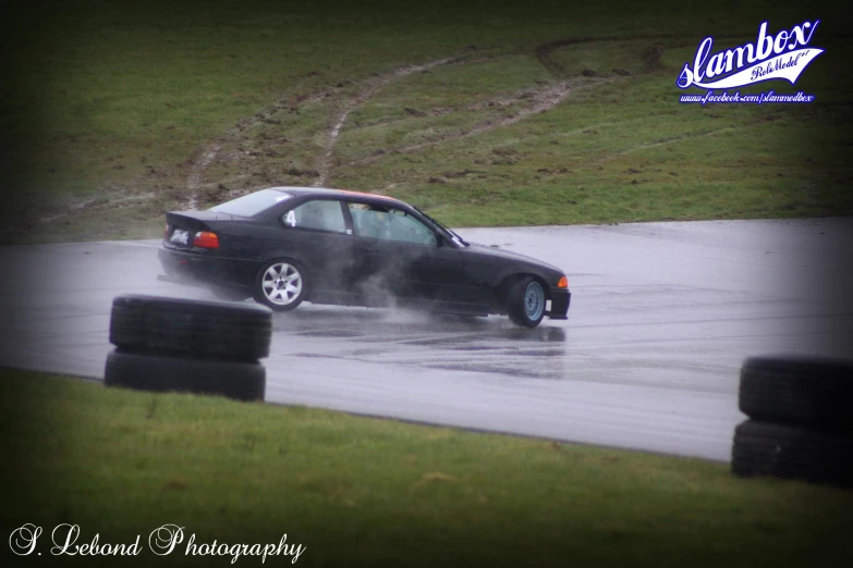 a black car driving through a dle of water