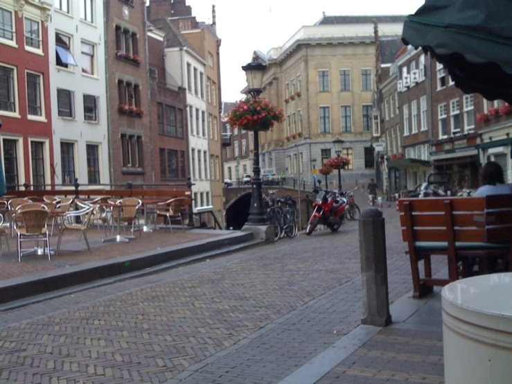 a street with brick and tables, chairs and umbrellas