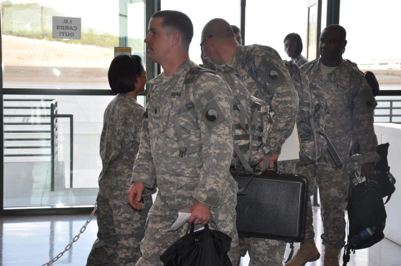 men in military uniforms are carrying their belongings