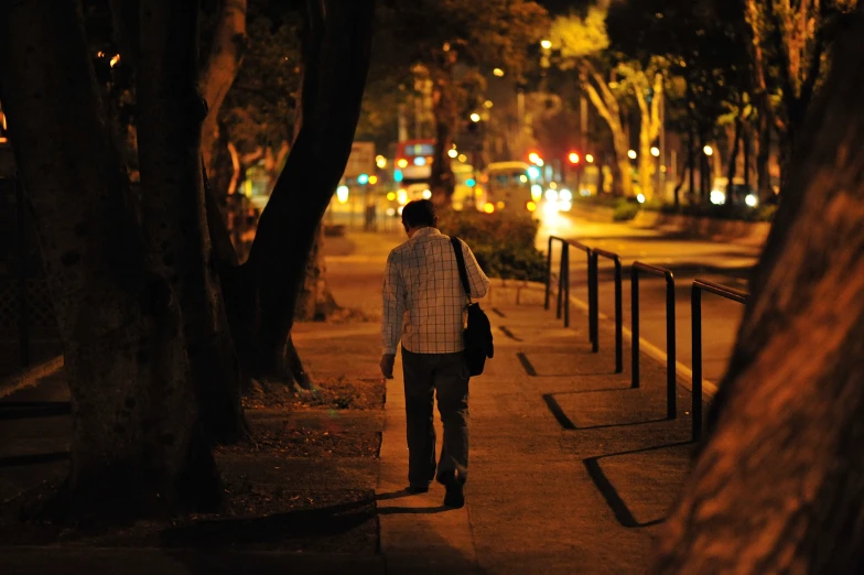 man walking on a sidewalk next to the woods