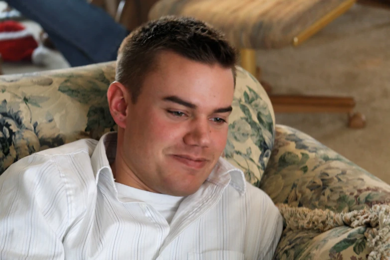 a young man sitting in a chair with his head slightly covered