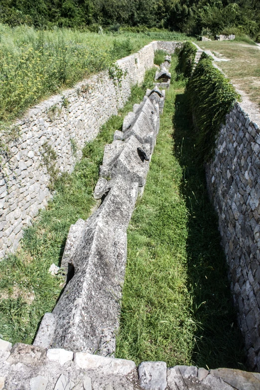 an ancient walkway between two walls in the grass