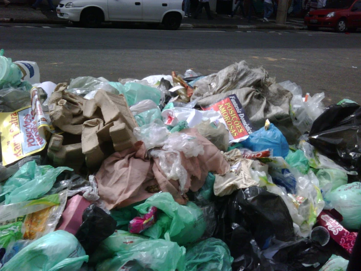 piles of plastic bags and garbage sitting next to the road