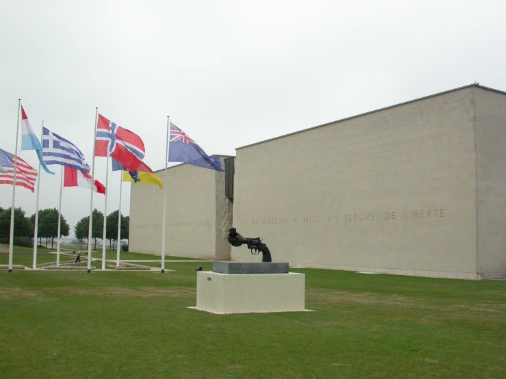 several different flags next to a gray building